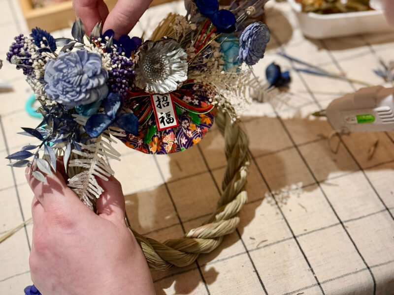 A close up of a person making a Japanese Shimenawa and filling it with flowers